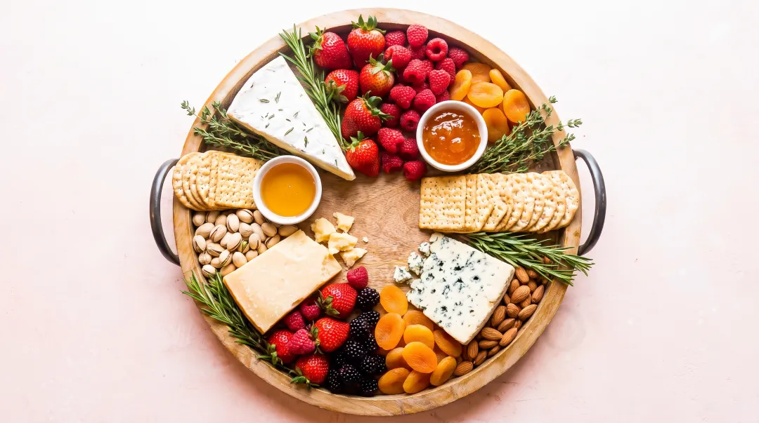 Elegantly arranged cheese board with varied textures crackers fruits nuts and fresh herb garnishes