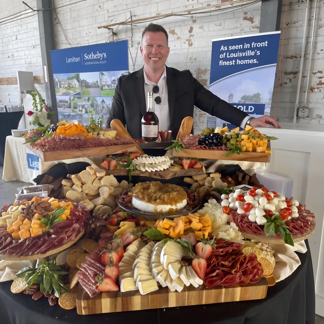 Bartender serving cocktails beside a catered grazing table