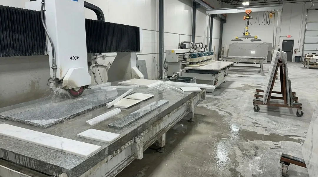 Bridge saw cutting granite slab in professional stone fabrication shop