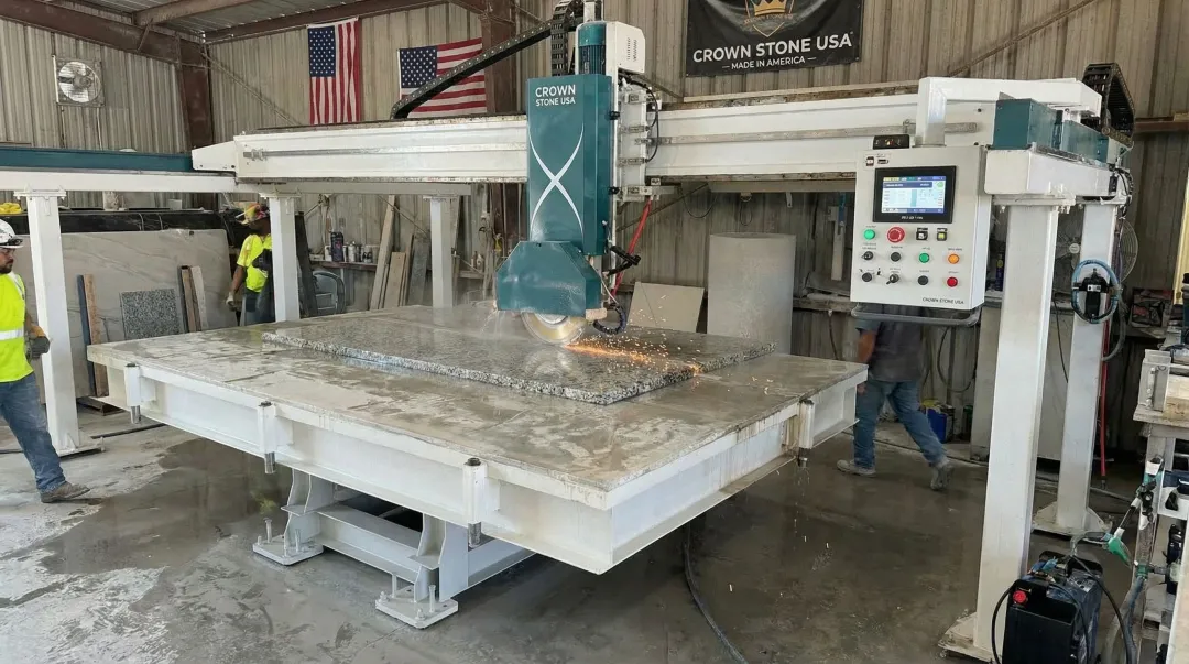 Crown Stone USA bridge saw machine on fabrication shop floor cutting granite slab
