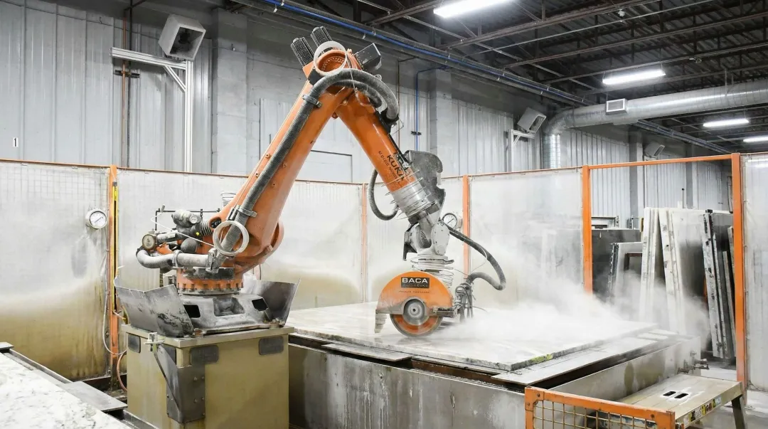 Robotic sawjet machine cutting stone countertop slab in high-volume fabrication shop