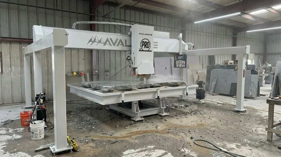 Heavy-duty bridge tile saw cutting large granite slab in fabrication shop