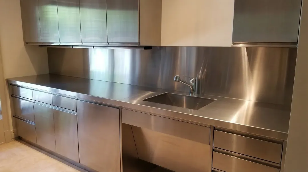 Custom stainless steel kitchen cabinets installed in high-end residential kitchen with integrated appliances