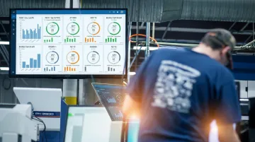 Manufacturing plant floor with operators using digital workflow dashboards and screens