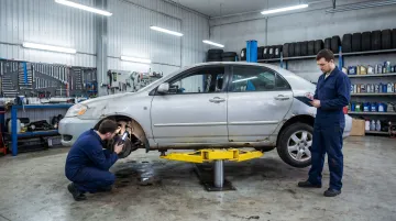 Aging high-mileage used vehicle on lift in auto repair shop showing mechanical wear