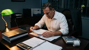 Overwhelmed business professional reviewing complex reinsurance liability documents at desk