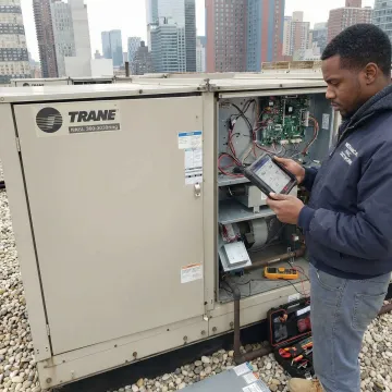 Trane RTU rooftop unit being serviced by a Denair HVAC technician in Brooklyn
