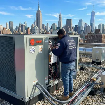 Certified technician servicing a Trane rooftop HVAC unit on a commercial building in Queens, NY