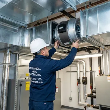 Certified HVAC technician replacing an inline duct fan in a Queens NY building