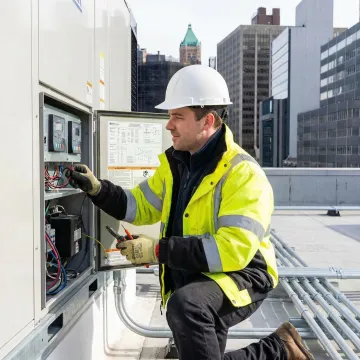 HVAC technician commissioning a commercial rooftop unit on a city building
