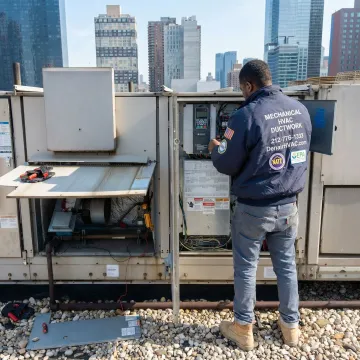 HVAC technician installing a variable frequency drive on a commercial HVAC unit in Long Island City