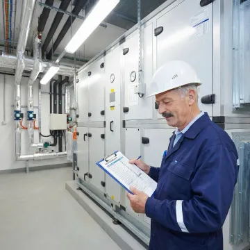 HVAC technician reviewing a maintenance checklist next to a commercial makeup air unit