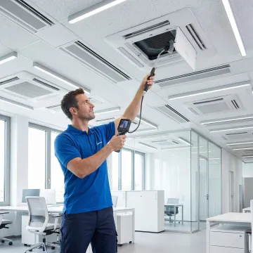 HVAC technician servicing indoor VRV fan coil units inside a commercial building