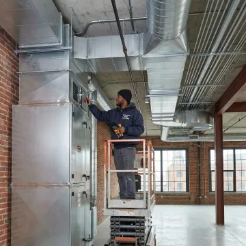 Commercial HVAC technician repairing ventilation ductwork in a Brooklyn commercial building