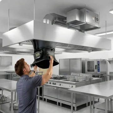 HVAC technician performing airflow testing on a commercial kitchen makeup air unit