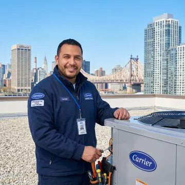 Carrier HVAC technician servicing a commercial rooftop unit in Long Island City, NY