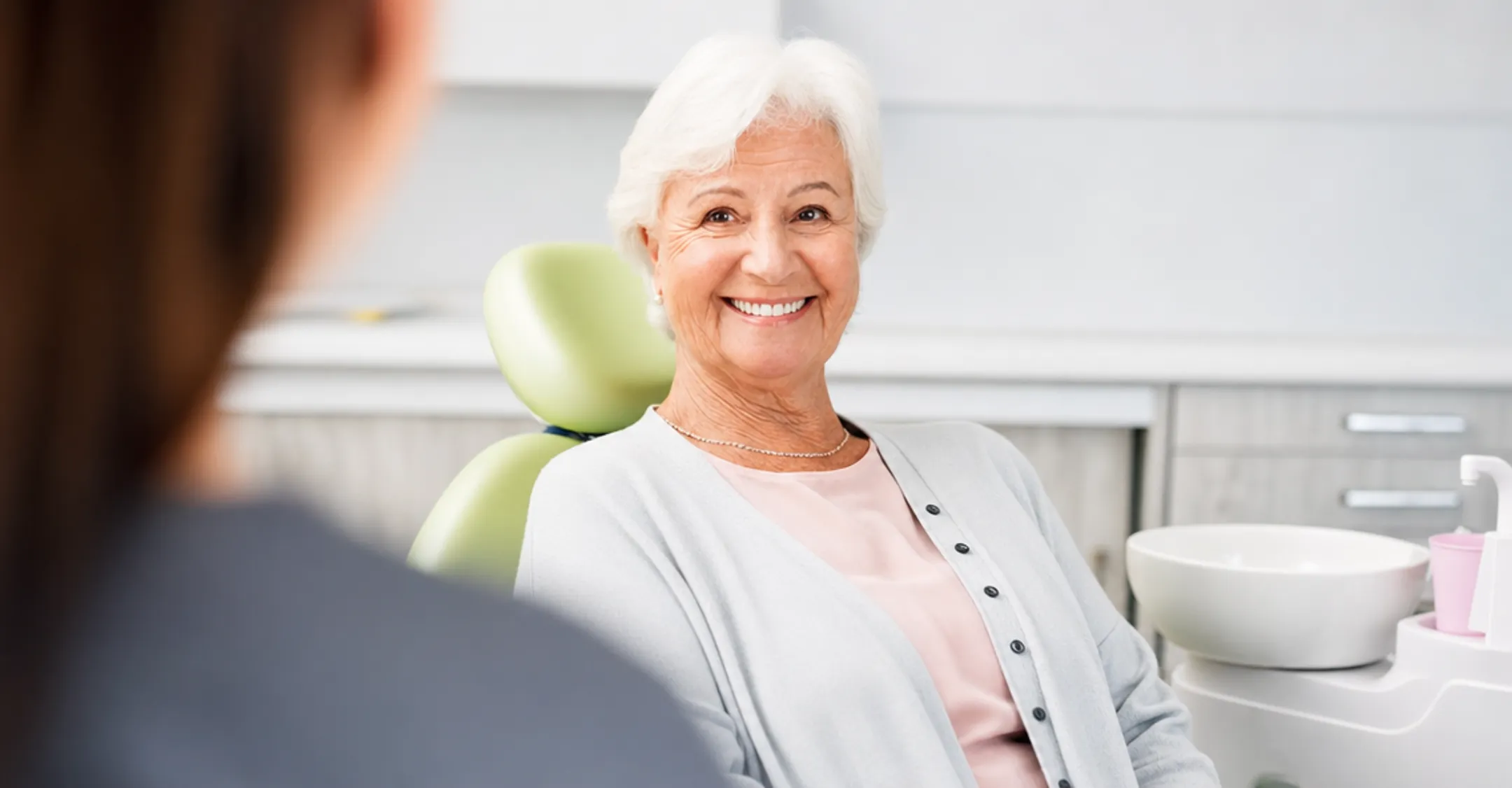 Dental patient smiling confidently after snap-on denture implant procedure