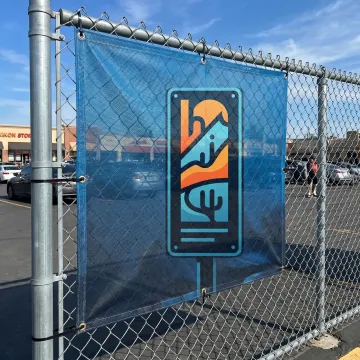 Custom mesh banner installed outdoors on a fence