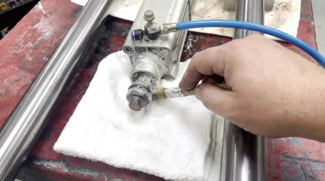 Technician testing reassembled pneumatic cylinder with soapy water leak detection method