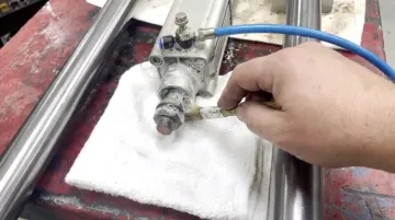 Technician testing reassembled pneumatic cylinder with soapy water leak detection method
