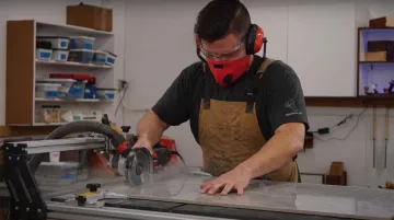 Worker wearing safety glasses and dust mask while cutting tile