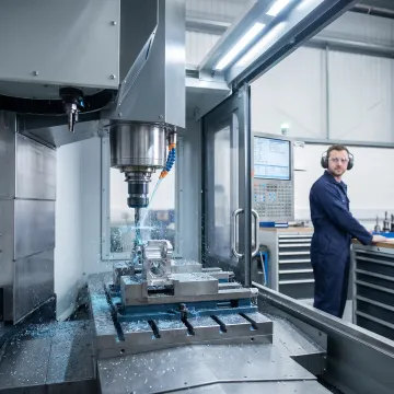 Vertical CNC milling machine producing a precision metal component in a manufacturing facility