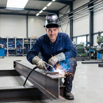 Skilled welder performing AWS certified specialty fabrication in an industrial machine shop