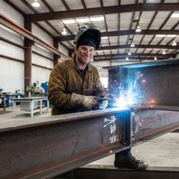 AWS certified welder performing precision welding on a large structural metal fabrication in a Michigan industrial facility
