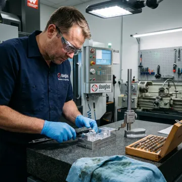 CNC machinist inspecting a precision metal part