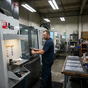CNC machinist working on precision metal components