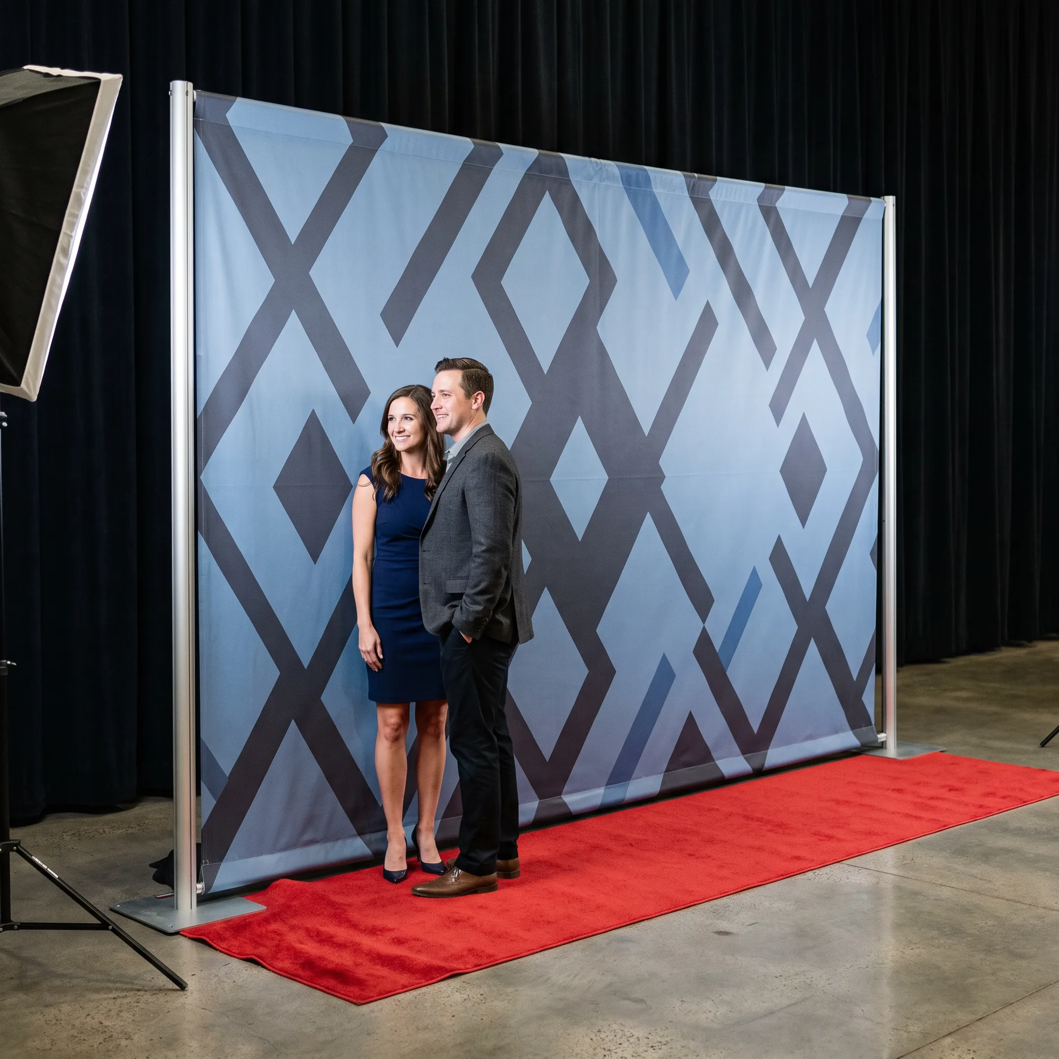 Custom branded step and repeat backdrop beside a red carpet at an event