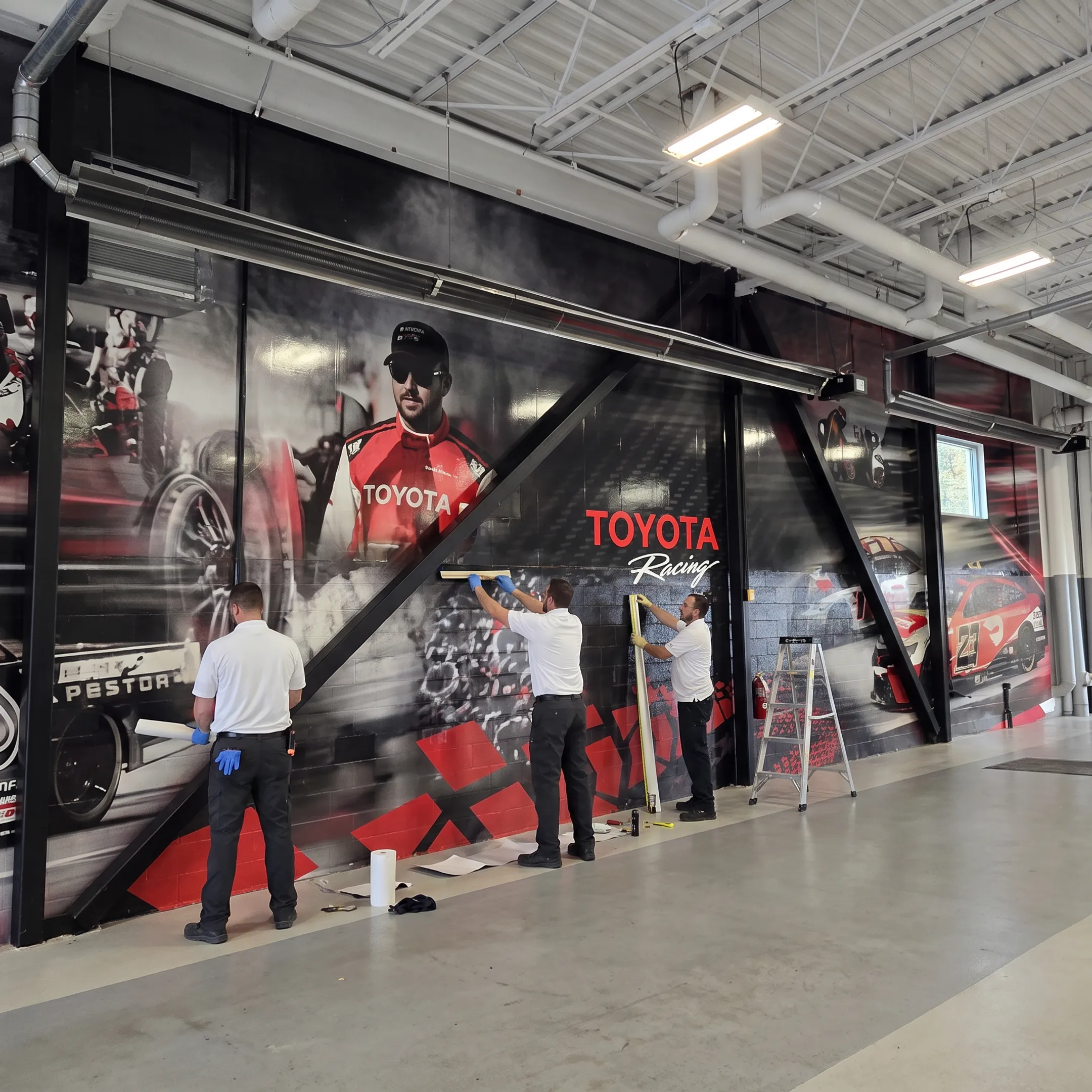 Technician installing a custom wall mural in a finished commercial space