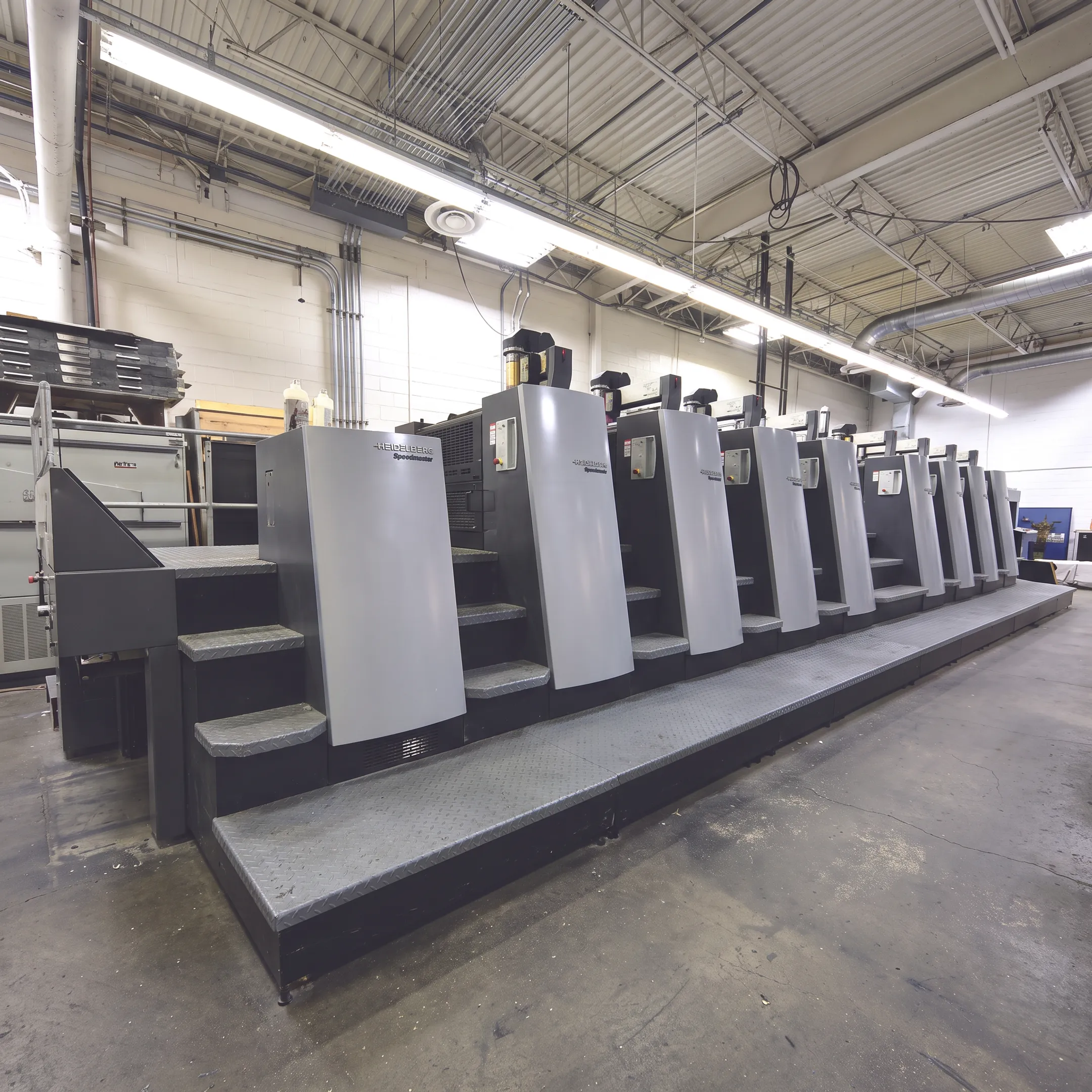 Printed publication pages arranged beside commercial printing equipment