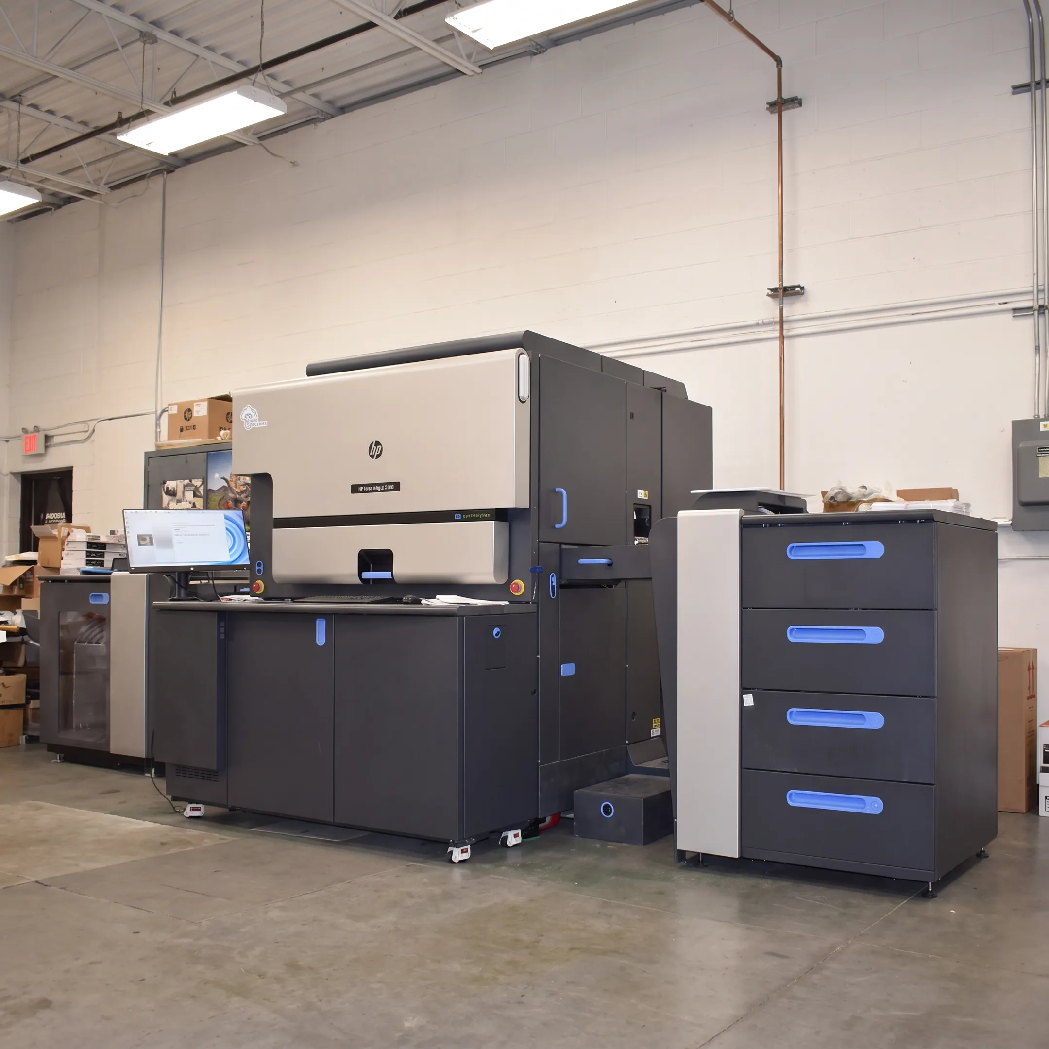 Printed brochures and personalized mail pieces arranged beside digital press equipment