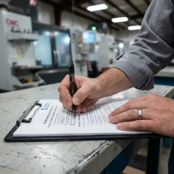 A checklist on a clipboard being marked with a pen, representing the ISO 9001 certification process.