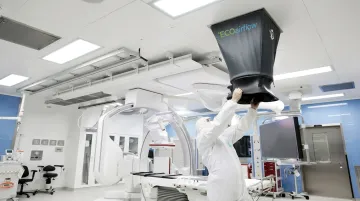 Facilities technician using balometer airflow measurement tool in hospital operating room