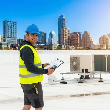 Roofing technician inspecting commercial roof damage in Austin