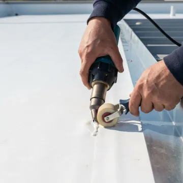 Industrial warehouse roof repair close-up showing membrane seam restoration work