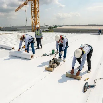 Commercial roofing crew repairing industrial flat roof on manufacturing facility