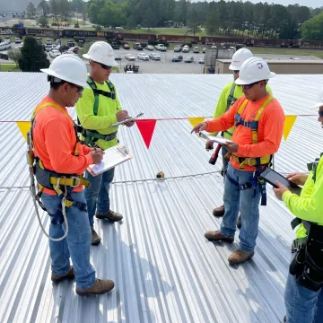 Roofing crew inspecting a warehouse roof