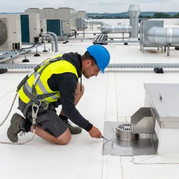 Technician inspecting a commercial flat roof membrane