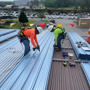 Commercial roofing crew installing replacement metal panels