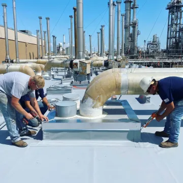 Commercial roofer installing flashing around rooftop equipment