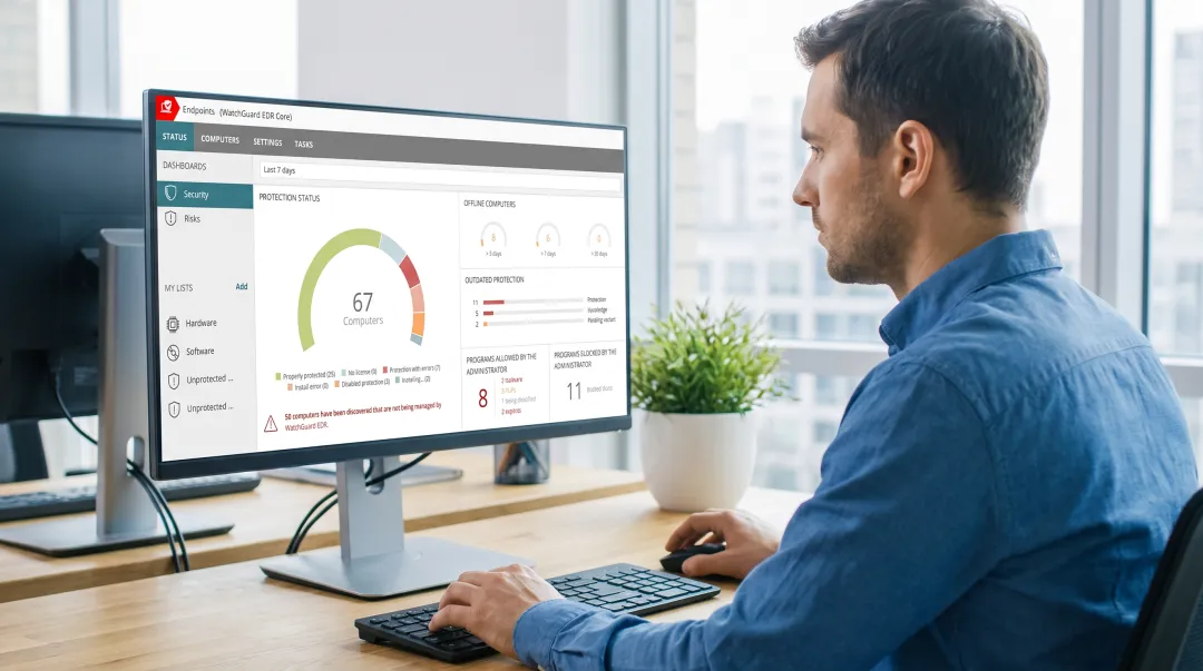 IT administrator monitoring endpoint security dashboard on multiple screens