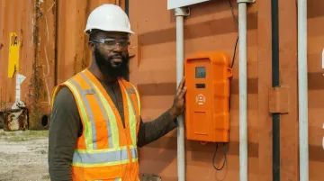 Rugged weatherproof construction time clock device mounted on jobsite fence