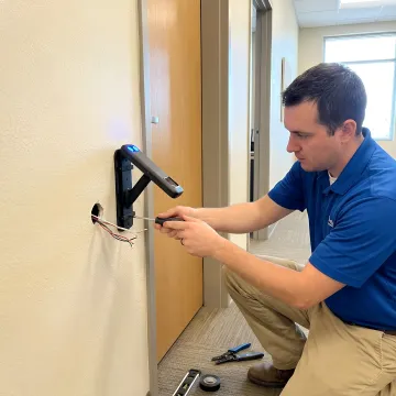 Professional installing contactless palm vein biometric scanner at secure facility entrance