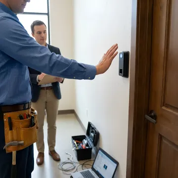Security consultant reviewing biometric access control system blueprint with facility manager