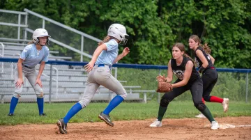 Softball players competing in live scrimmage situation with runners on base during practice
