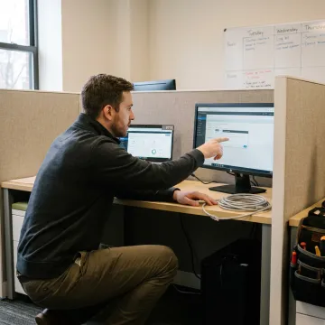 Professional computer support technician assisting office staff