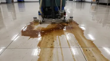 Commercial robotic floor scrubber leaving visible streaks on polished warehouse floor
